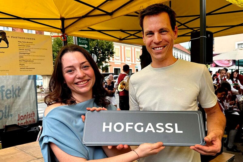 Zwei Personen halten das neue Straßenschild Hofgassl