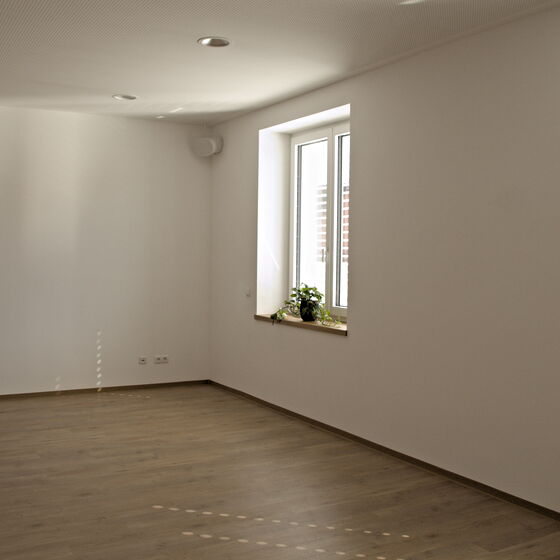 Bewegungsraum im 1. Obergeschoss mit zwei Fenstern und Holzboden