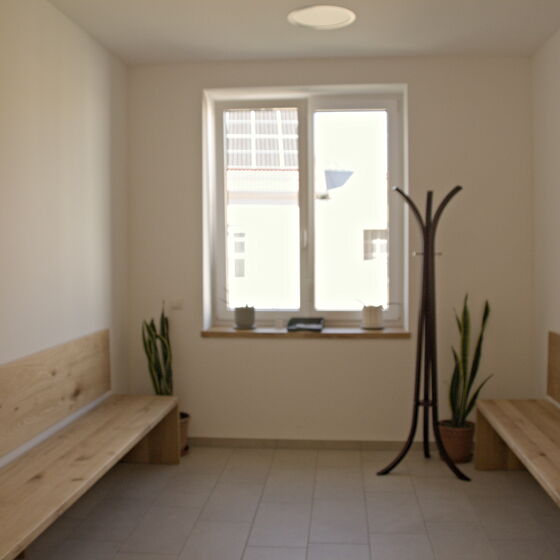 Wartebereich mit Sitzbänken aus Holz und Garderobe