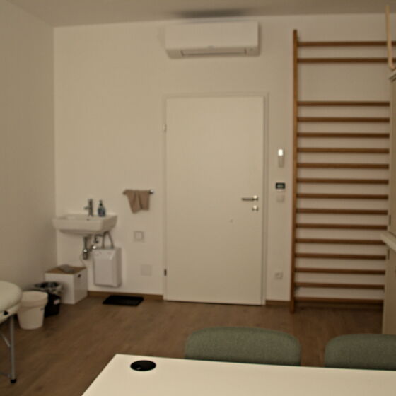 Behandlungsliege, Waschbecken und Sprossenwand im Therapieraum
